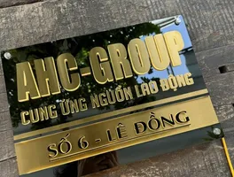 Bảng hiệu công ty inox vàng xước chữ nổi 3D LED halo – nhìn tổng thể mặt trước Bảng hiệu công ty AHC Group inox vàng xước nền đen chữ nổi 3D đèn LED halo backlit