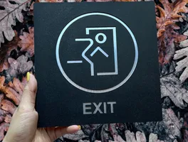 Biển exit inox 304 sơn tĩnh điện – mặt trước chính diện sắc nét Biển exit inox 304 sơn tĩnh điện đen mặt trước chính diện, icon ISO 7010 và chữ EXIT cắt CNC